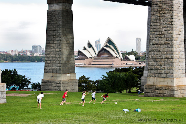 Kids playing soccer under Sydney Harbour Bridge, Opera House in the background