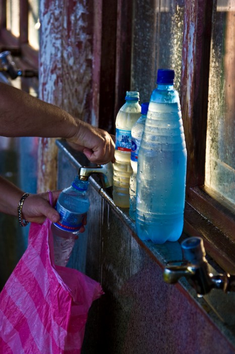 Filling bottles with cold refreshing mineral water from the tap